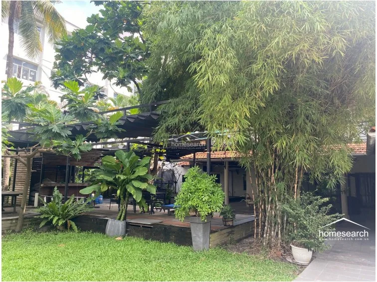This perspective highlights the property's exterior, showcasing a wooden deck area nestled among dense bamboo and tropical greenery. The integration of the deck with the natural landscape creates a tranquil outdoor sanctuary, emphasizing a strong connection between the home's architecture and its lush surroundings.