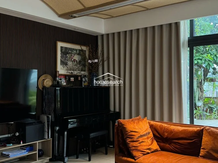 This living room features a sophisticated open-plan layout that flows seamlessly into an adjacent dining or kitchen area through a dark-toned transition space. The room is highlighted by a unique arched, rattan-textured ceiling and large floor-to-ceiling windows that provide ample natural light and a view of a lush terrace garden.