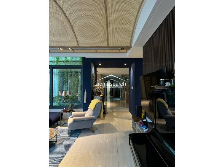 This view highlights the architectural transition between the living area and the rest of the home, marked by a bold navy blue wall that frames the hallway. The interior maintains a high level of maintenance, featuring integrated ceiling lighting and a neutral color palette that balances the dark accent walls and rich furniture tones.