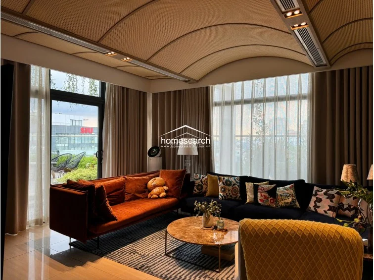 The living room layout is spacious and well-organized, comfortably accommodating multiple seating zones including a plush armchair and a large L-shaped sofa. The integration of concealed air conditioning within the ceiling design ensures a clean aesthetic, while the proximity to the outdoor terrace provides a seamless indoor-outdoor living experience.
