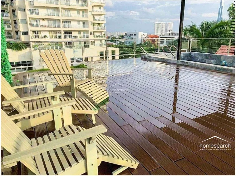 This spacious rooftop terrace is finished with high-quality dark wood decking and features a built-in plunge pool or water feature. It offers an expansive outdoor seating area with lounge chairs, providing an elevated view of the surrounding urban skyline.