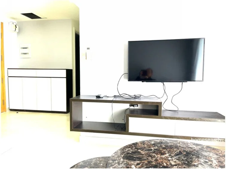 This image shows a living area featuring a modern, two-tone floating media console in dark wood and white. The wall is finished in a clean, neutral white, and the flooring consists of light-colored, large-format tiles. A marble-topped coffee table is partially visible in the foreground, suggesting a contemporary and compact layout.