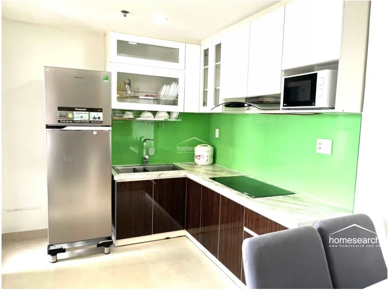 This kitchen layout provides a compact and efficient workspace that flows directly into the adjacent dining area. The design maintains a clean, contemporary look with ample storage provided by the overhead cabinets and a built-in microwave nook.