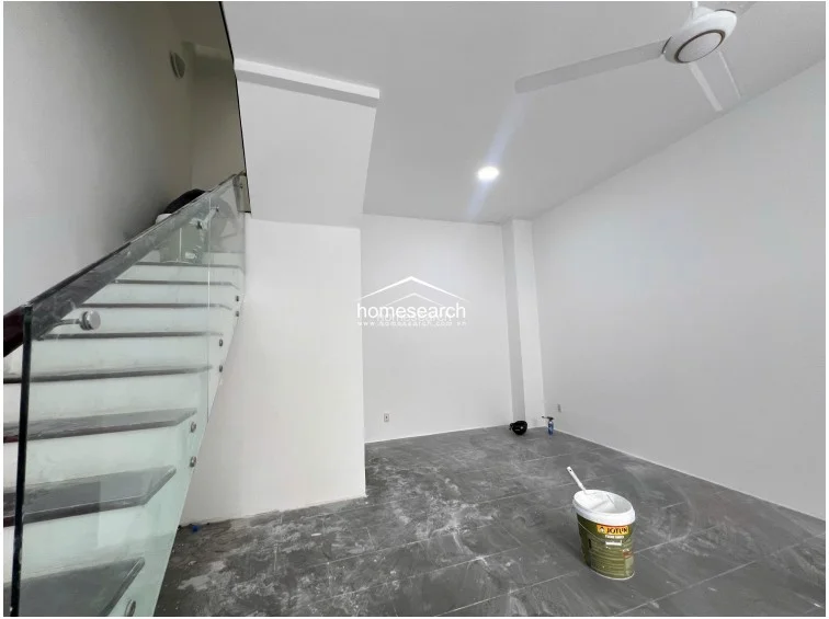 This close-up of the staircase highlights the modern design, featuring a glass balustrade with stainless steel hardware and dark-toned treads. The area is finished with high-quality white paint and recessed lighting, reflecting a well-maintained, contemporary architectural style.