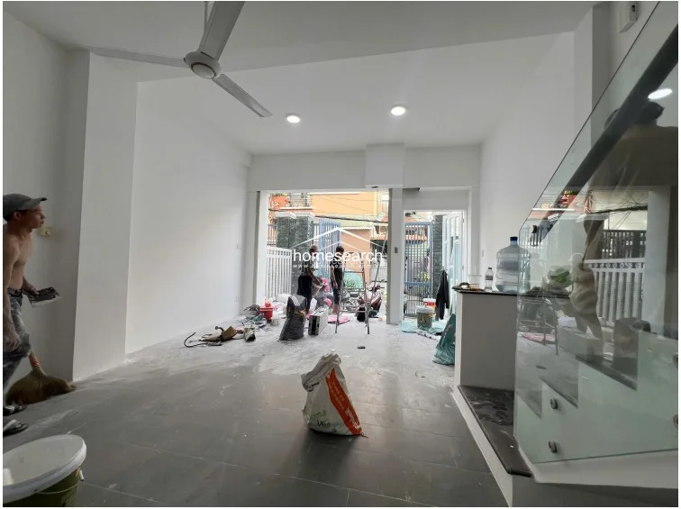 This ground-level perspective emphasizes the depth of the open-plan floor, which extends from the staircase to the front gate. The area is currently being prepared for occupancy, showcasing a bright, airy atmosphere with neutral finishes and functional, modern lighting fixtures.