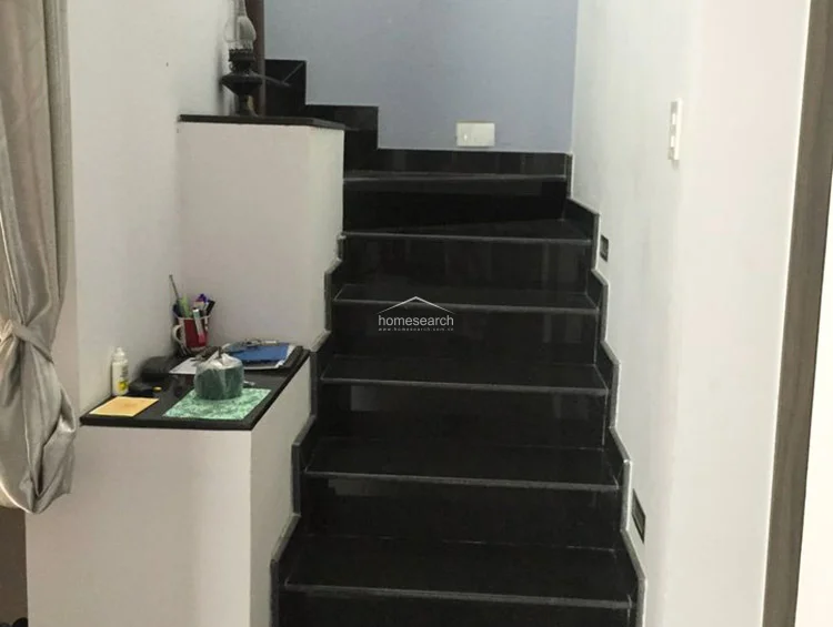 This image shows an interior staircase featuring polished black stone steps that contrast sharply against the clean white walls. A small built-in ledge at the base of the stairs serves as a functional surface for personal items, and the overall condition appears well-maintained and modern.