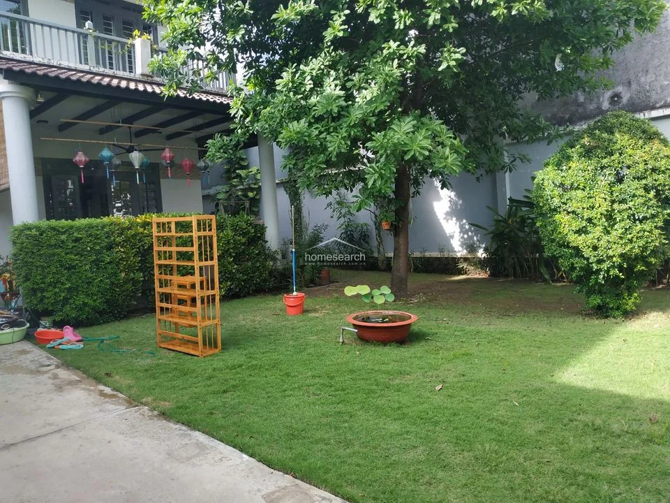 This shot highlights the serene garden space, which includes a mature tree, a decorative water feature, and a well-manicured lawn. The area connects directly to the home's covered patio, creating a seamless transition between indoor and outdoor living spaces.