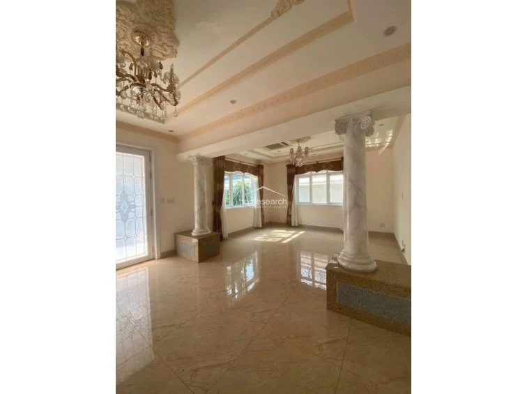 This transitional space highlights the home's neoclassical architectural details, featuring two prominent marble-finished columns set on raised plinths. The area maintains a consistent luxury aesthetic with high-gloss marble flooring, ornate ceiling plasterwork, and a warm, inviting color palette that flows into the surrounding rooms.
