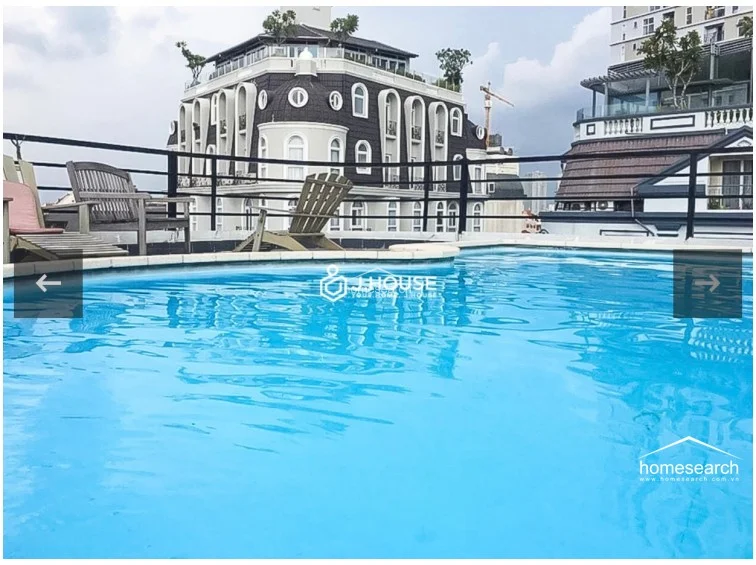 This rooftop terrace features a refreshing swimming pool that offers an open-air relaxation space with views of neighboring architectural buildings. The area is equipped with wooden lounge chairs, providing a comfortable setting for leisure while being enclosed by a functional black metal safety railing.