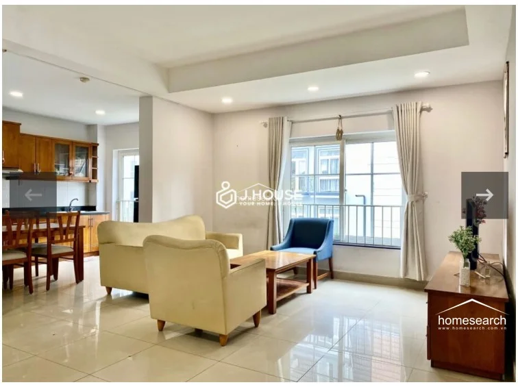 This open-concept living and dining area features polished light-colored tile flooring and neutral wall tones, creating a bright and airy atmosphere. The space is well-lit by recessed ceiling lights and a large window with floor-to-ceiling curtains that offers a view of the neighboring building.