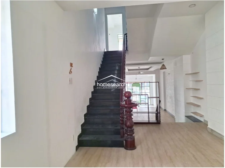 This shot captures the full verticality of the staircase, which serves as a central architectural feature connecting the levels. The layout emphasizes an open, airy feel with high ceilings, recessed lighting, and a consistent use of wood-look flooring, creating a cohesive and functional transition between the front living space and the rear of the property.