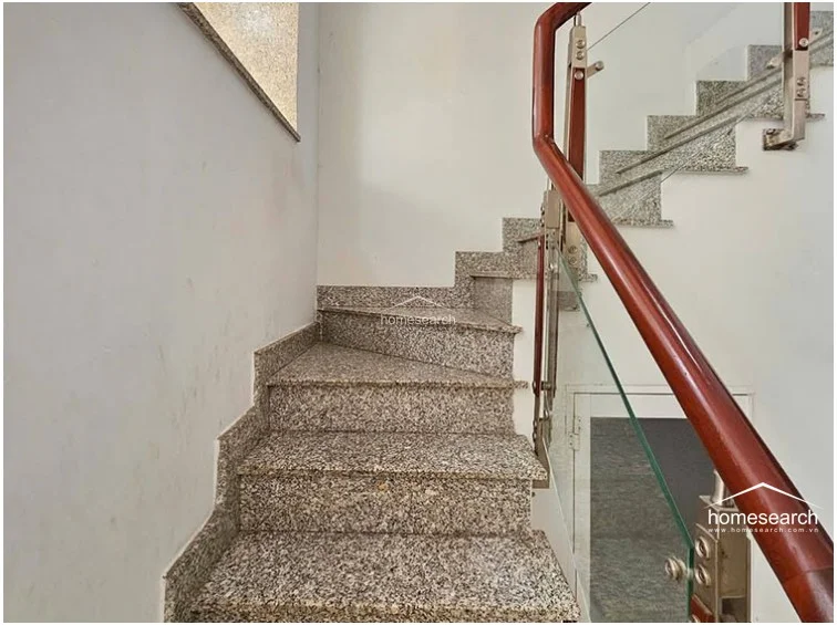 This staircase features durable granite steps paired with a modern glass balustrade and a polished wooden handrail. The design provides a clean, contemporary aesthetic that allows for an open flow between levels while maintaining a sturdy, high-quality finish.