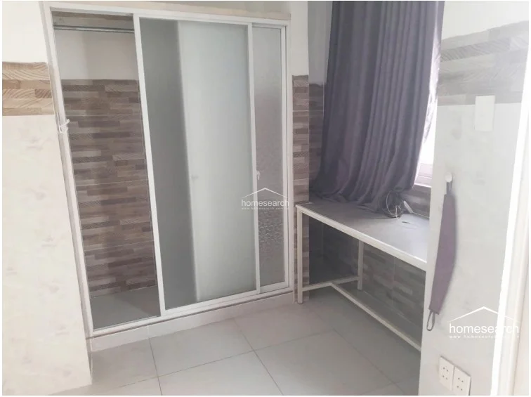 This area shows a built-in closet with frosted glass sliding doors and a metal-framed desk or console table. The space continues the theme of white tiled floors and walls with horizontal brown accent tiles, maintaining a clean and functional aesthetic.