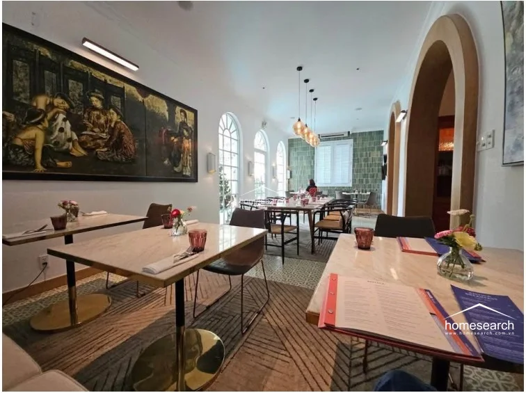 This elegant dining room showcases a bright, airy layout with arched windows that allow for ample natural light and a view of the exterior. The space is finished with white walls, patterned tile flooring, and sophisticated pendant lighting, creating a refined atmosphere for dining.