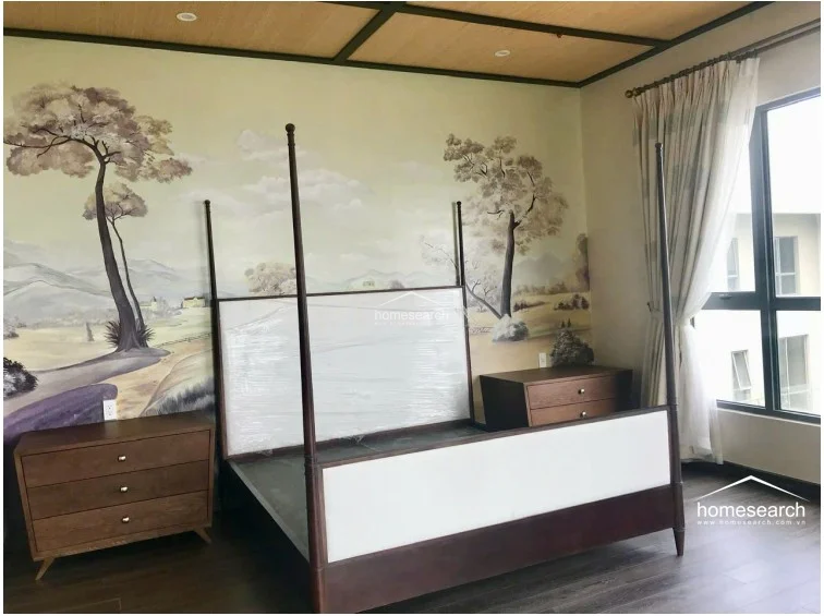 The bedroom is highlighted by a striking, large-scale landscape mural on the main wall, complemented by a classic four-poster bed frame. It features dark wood flooring, a warm wood-slat ceiling, and large windows with sheer curtains that allow for soft, natural light.