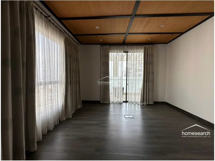 This bedroom features dark wood-look flooring and a distinctive coffered ceiling with woven inserts. Large windows draped in floor-to-ceiling sheer and opaque curtains provide ample natural light and direct access to a balcony.
