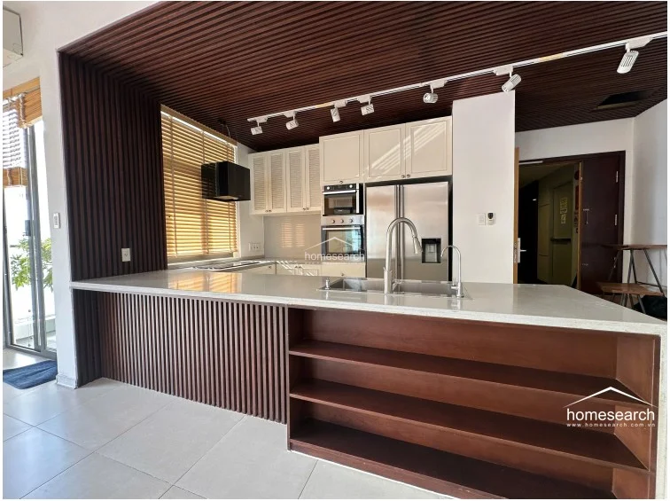 This modern kitchen features a sleek peninsula layout with a white stone countertop and integrated open shelving for storage. The space is accented by a sophisticated dark wood-slatted ceiling and matching wall paneling, complemented by stainless steel appliances including a built-in oven and microwave.