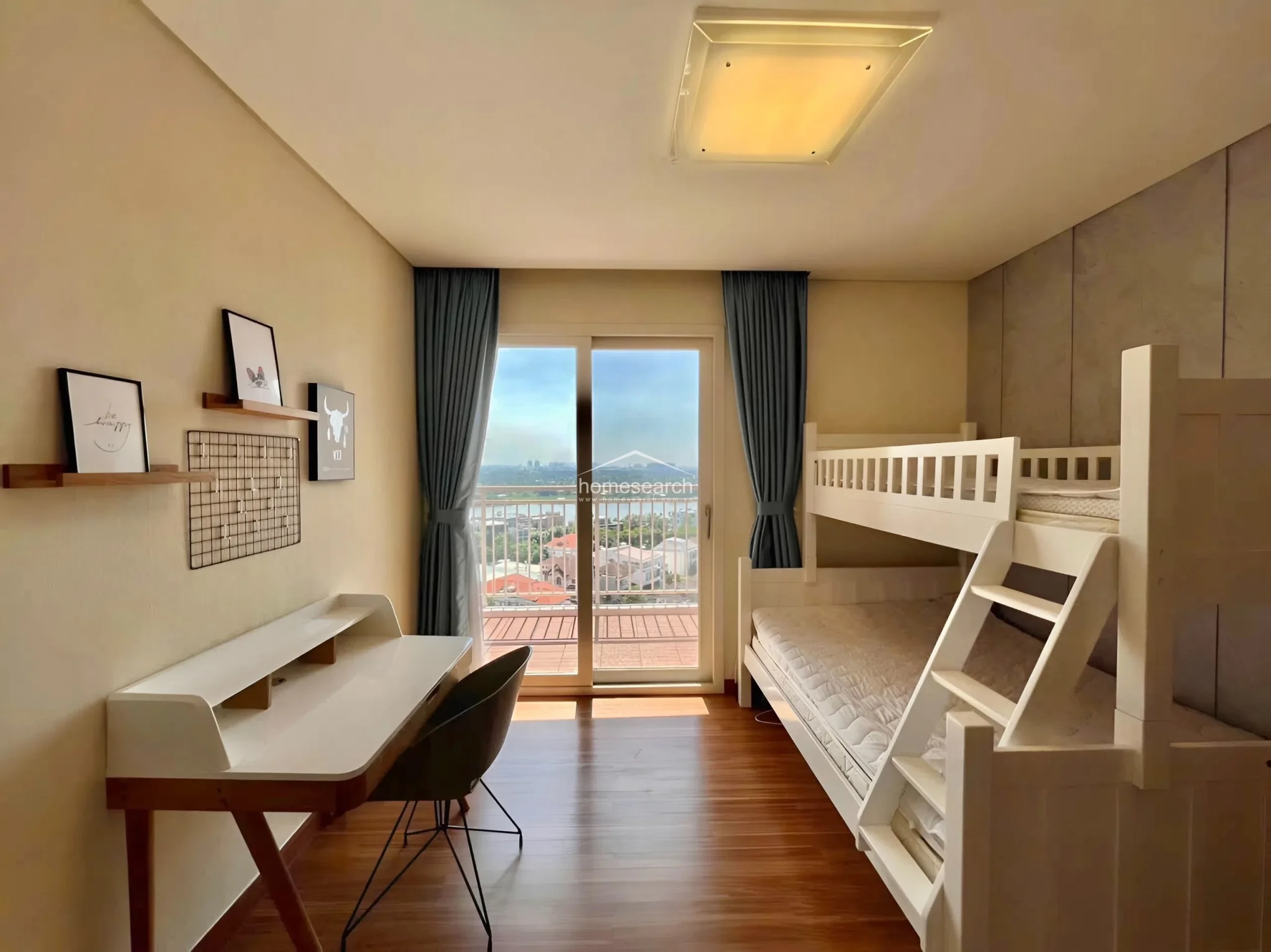 This functional bedroom is designed with a white bunk bed and a matching desk, making it an ideal space for children or guests. It features wood-look flooring, neutral wall tones, and floor-to-ceiling sliding glass doors that provide direct access to a balcony and plenty of natural light.