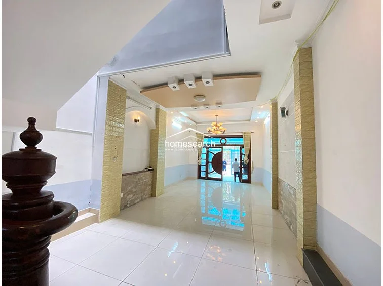 This shot provides a reverse perspective of the living area, highlighting the transition from the front entrance into the central hall. The room is accented by decorative columns with textured stone cladding and maintains a consistent, well-maintained aesthetic throughout the open floor plan.