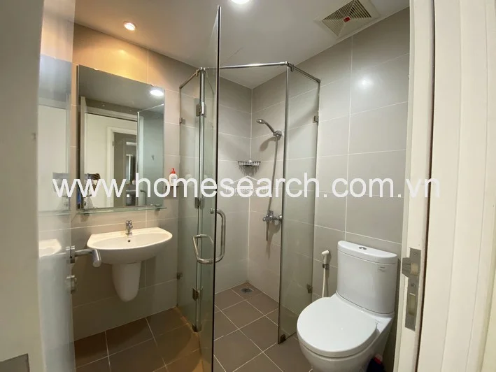 This bathroom mirrors the previous layout, showcasing a clean, contemporary design with a glass shower stall and efficient use of space. The neutral color palette and recessed lighting create a bright, hygienic environment, complemented by functional fixtures and a pedestal sink.