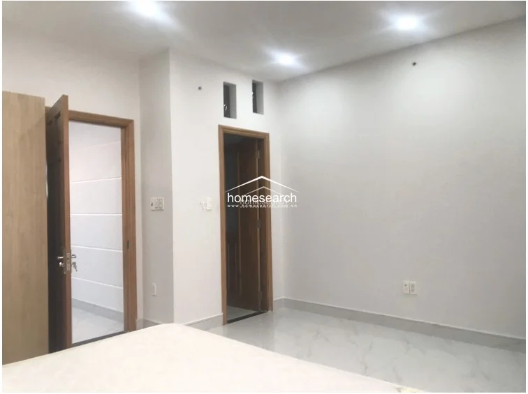 This shot reveals the room's connectivity, showing doorways that lead to adjacent areas of the home. The space remains bright and uncluttered, featuring recessed lighting and a simple, modern design that allows for versatile furniture placement.