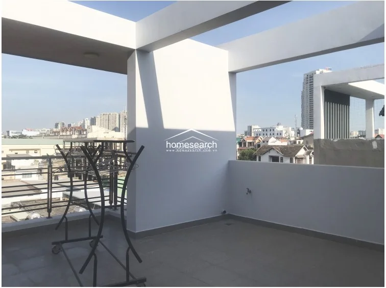 This terrace area serves as a functional outdoor space, likely used for laundry, and is finished with durable grey floor tiles. It is bordered by a metal railing and white walls, offering a clear, unobstructed view of the city skyline.
