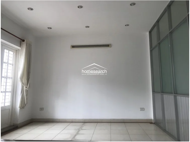 This versatile room or office space includes a wall-mounted air conditioning unit and large glass partitions for a modern, open feel. The room is finished with white walls and light-colored floor tiles, offering a bright and flexible layout that connects seamlessly to the rest of the property.