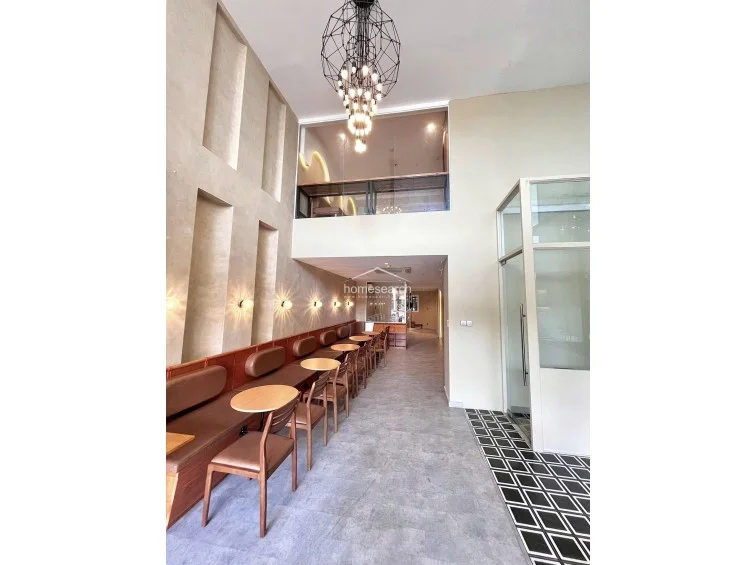 This view emphasizes the architectural depth of the room, showcasing a mezzanine level that overlooks the main dining floor. The wall features recessed vertical niches that add texture and dimension, while the overall condition appears well-maintained with a sophisticated, contemporary aesthetic.