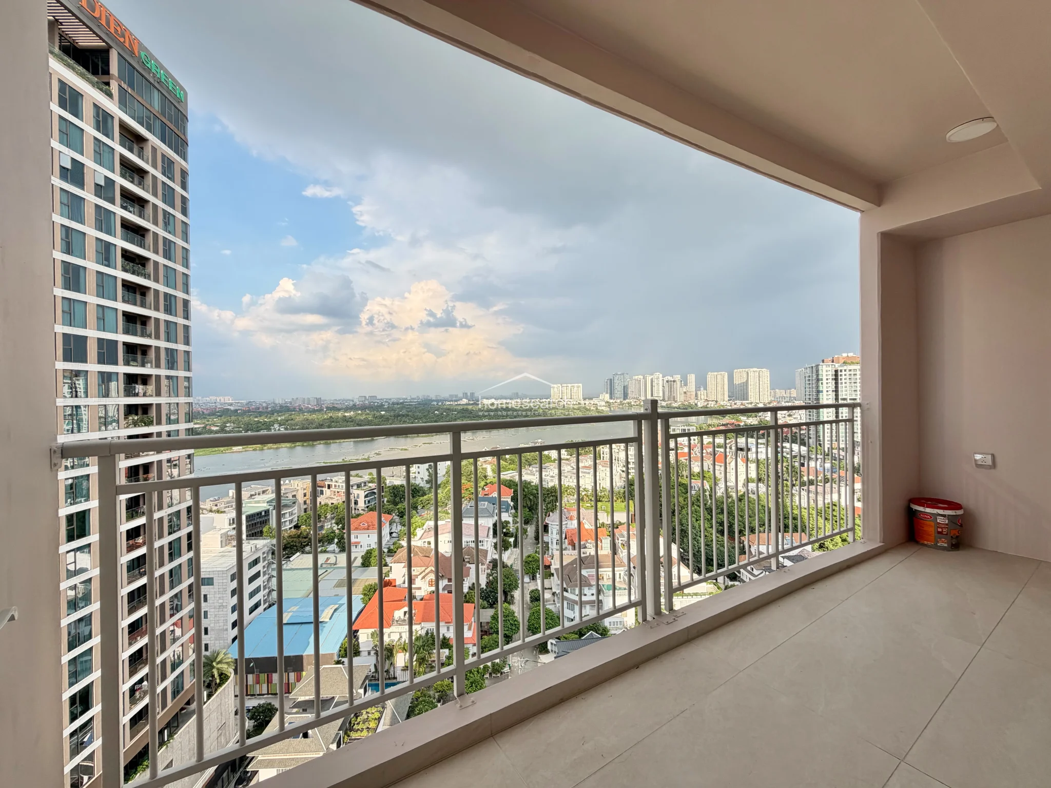 This spacious balcony offers an expansive, unobstructed view of the surrounding cityscape and river, providing a perfect outdoor retreat. The area is finished with neutral, durable tile flooring and a sturdy metal railing, reflecting a high level of maintenance and modern architectural design.
