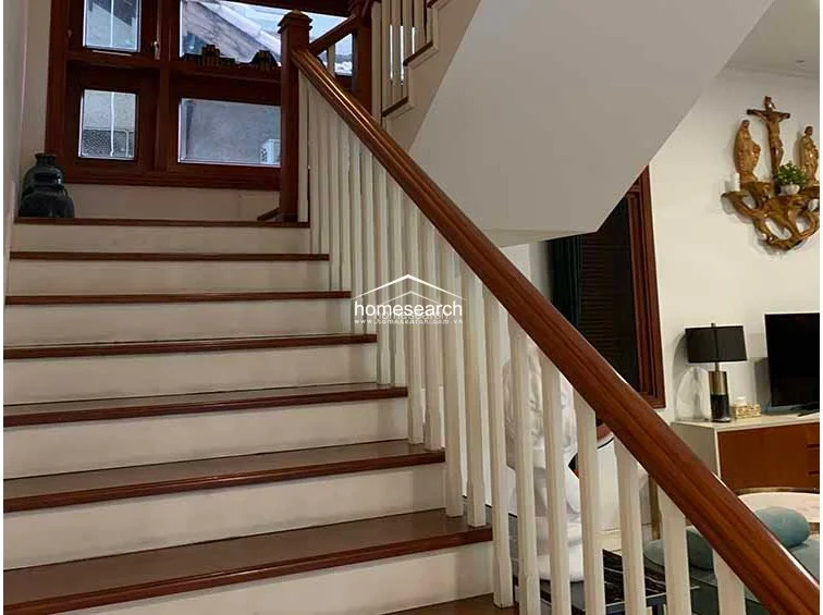 This staircase area showcases a classic design with white balusters and a polished wooden handrail, creating a strong architectural focal point. The space is well-maintained and decorated with tasteful wall art, connecting the different levels of the home with a warm, inviting aesthetic.