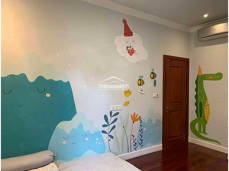 This child's bedroom continues the vibrant, artistic theme with a large wall mural depicting mountains, clouds, and a friendly crocodile. The room is equipped with a wall-mounted air conditioning unit and maintains a consistent, high-quality finish with dark wood flooring and crown molding.