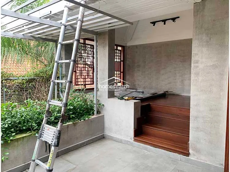 This section of the terrace features a raised wooden platform with steps, suggesting a designated area for relaxation or a daybed. The combination of raw concrete walls, warm timber flooring, and integrated track lighting creates a sophisticated, industrial-chic atmosphere.