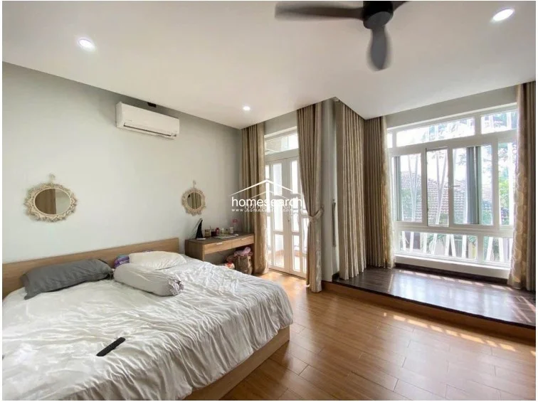This angle highlights the bedroom's cohesive design, featuring light-colored walls and wood-patterned flooring that creates a cozy atmosphere. The room flows directly to a private balcony, offering a seamless transition between indoor comfort and outdoor space.
