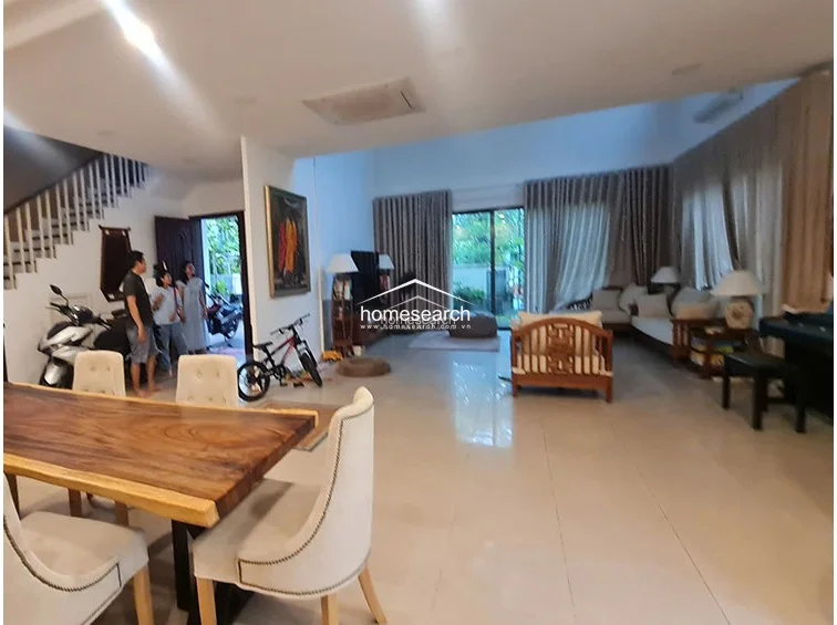 This angle captures the expansive living room, showcasing the generous floor space and the connection between the dining area and the lounge. The high ceilings and large glass doors ensure the room remains bright and inviting, while the minimalist decor keeps the area feeling uncluttered. The home is in good condition, featuring modern climate control and a layout that facilitates easy movement between zones.