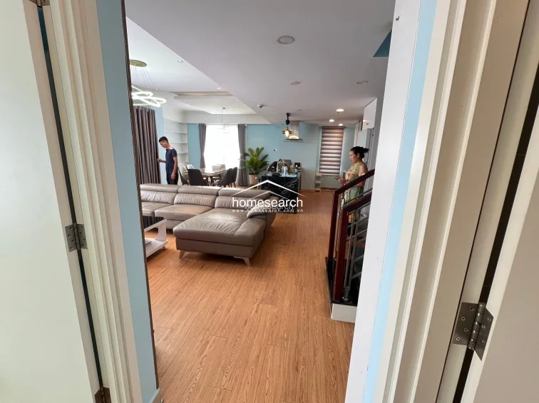 This view from the doorway highlights the seamless flow between the entryway and the main living space, emphasizing the open floor plan and recessed ceiling lighting. The transition between the tiled entryway and the wood-look flooring defines the functional zones, while the staircase provides a clear architectural connection to other levels of the home.