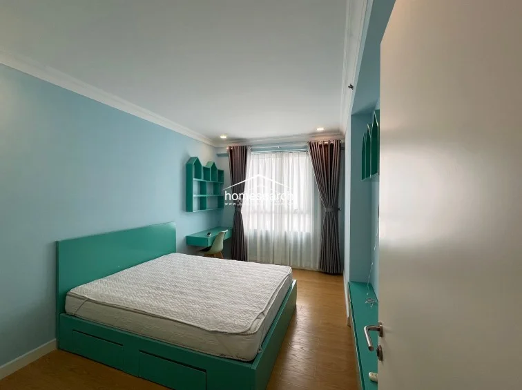 This bedroom layout highlights a teal-themed furniture set, including a bed with under-storage and a built-in desk with wall-mounted shelving. The space is brightened by a large window with floor-to-ceiling curtains, maintaining a consistent, playful, and organized design throughout.