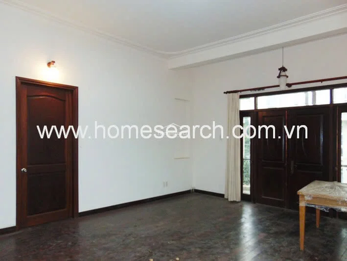 This view shows a continuation of the living space, highlighting a solid dark wood interior door and a matching set of double glass doors that open to the exterior. The room maintains a consistent aesthetic with white walls, crown molding, and dark wood flooring throughout.