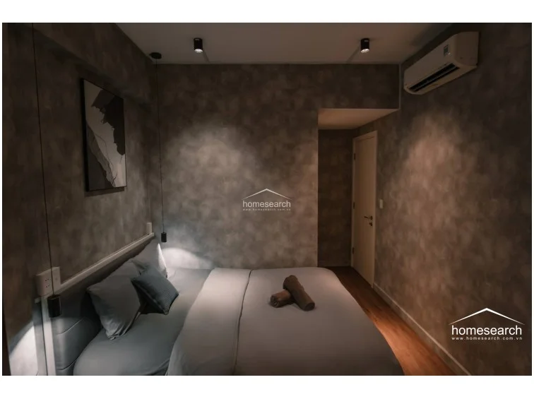 This view highlights the bedroom's integration of lighting, featuring both ambient ceiling spotlights and focused bedside pendants. The overall condition is excellent, presenting a stylish and move-in-ready space for a single occupant or couple.