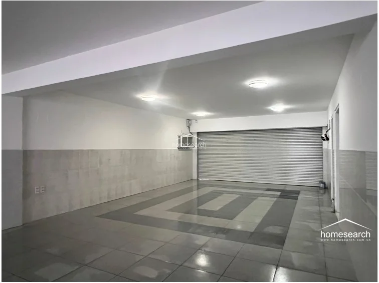 The ground-floor garage provides a spacious, climate-controlled storage area with a split-system AC unit and durable tiled flooring. The walls are finished in a neutral two-tone scheme, and the space is well-lit with recessed ceiling fixtures, indicating a well-maintained and functional utility area.