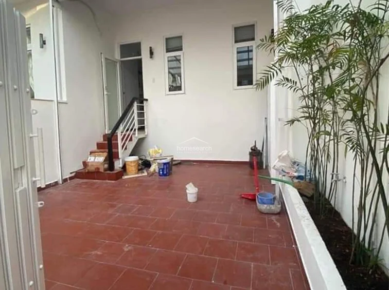 This view of the same terrace shows a dedicated planting bed along the wall, which adds greenery to the outdoor space. The area is currently undergoing minor maintenance or organization, with clear access to the interior via a staircase and doorway.