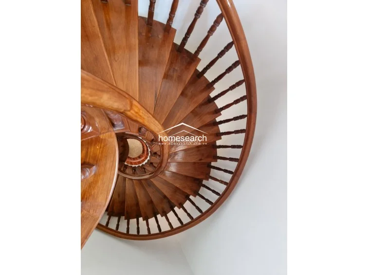 This top-down view showcases a beautifully crafted spiral staircase made of polished dark wood. The architectural detail of the curved steps and matching wooden railing adds a sophisticated, traditional element to the home's interior design.
