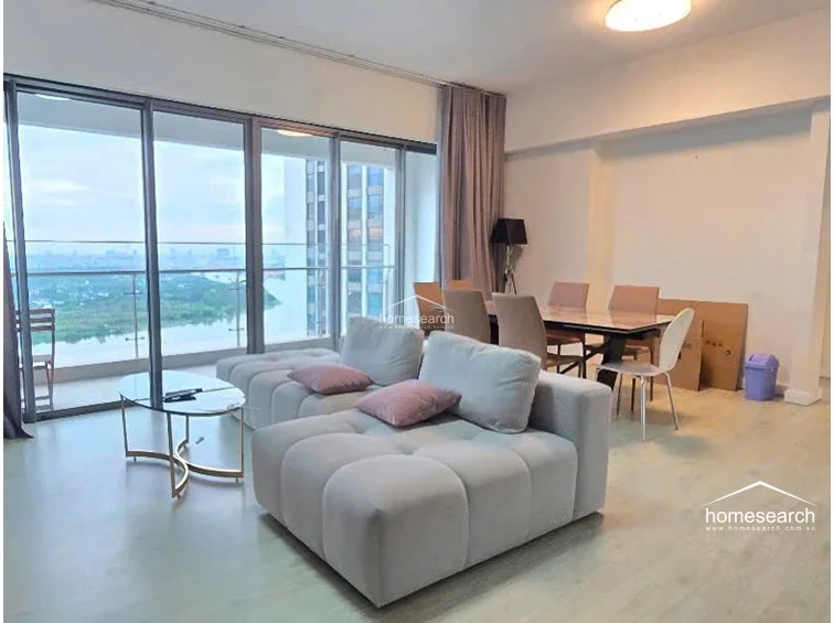 This alternate angle of the living room highlights the seamless flow between the dining and lounge areas, emphasizing the bright, airy atmosphere created by the large windows. The room maintains a minimalist aesthetic with a sleek TV console and a modern tripod floor lamp, all kept in excellent, well-maintained condition.