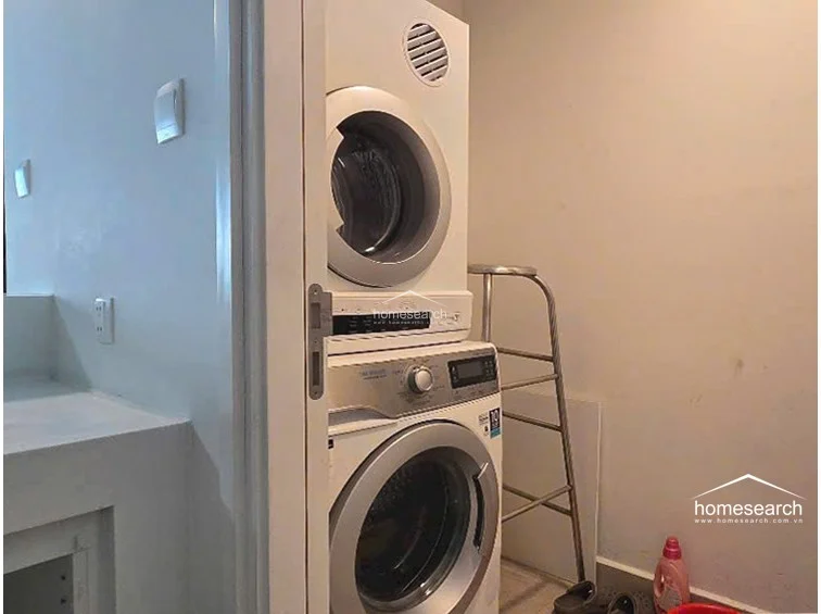 This utility area houses a stacked washer and dryer unit, providing a space-efficient laundry solution. The area is finished with simple, light-colored walls and appears to be a functional, dedicated space for household maintenance.