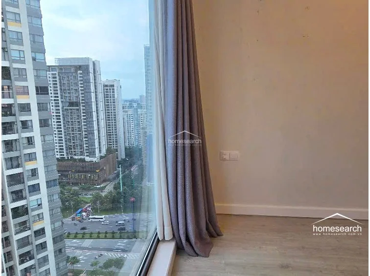 This view highlights the corner window placement, which maximizes natural light and offers a striking perspective of the neighboring high-rise buildings and the river below. The neutral color palette and minimalist wall finishes create a calm, uncluttered atmosphere suitable for a primary bedroom.