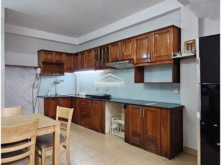 The kitchen features extensive wooden cabinetry providing ample storage, paired with a dark countertop and a light-colored backsplash. It is an open-concept layout that flows directly into the dining area, creating a practical and well-connected space for daily use.