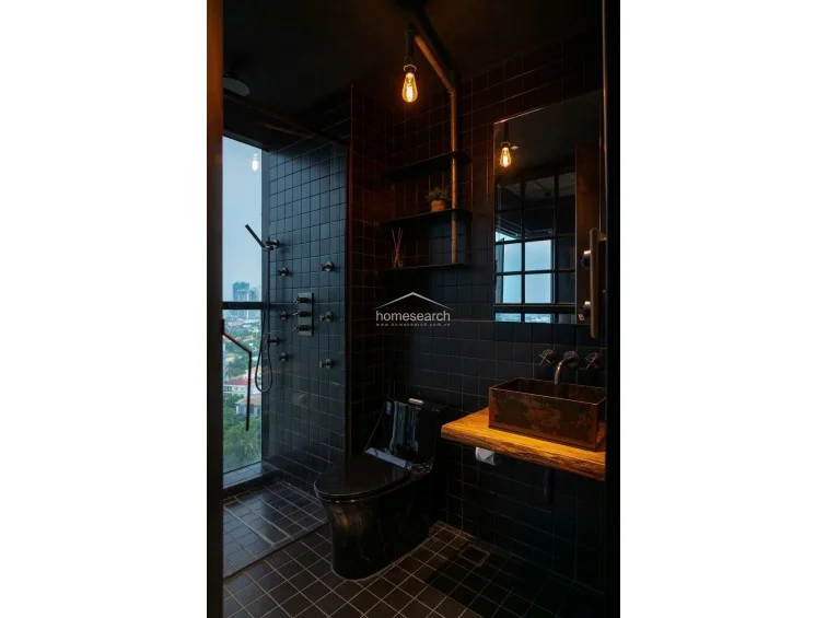 This industrial-style bathroom features a walk-in glass shower enclosure with a rain showerhead, accented by mosaic tile walls and a sleek concrete-style vanity. A high-set horizontal window provides natural light, while the dark color scheme and rivet-detailed door maintain a moody, modern aesthetic.