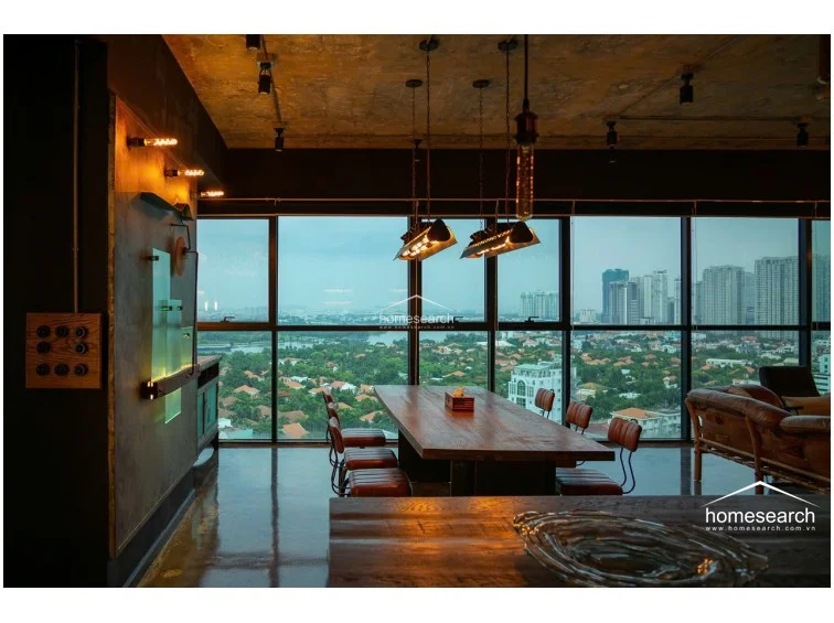 This perspective captures the dining area's connection to the rest of the loft, showcasing the thoughtful placement of furniture and lighting. The polished concrete floors reflect the natural light from the expansive windows, enhancing the sense of depth and scale in the room. The decor is highly stylized with vintage-inspired switches and wall art, reflecting a high level of attention to detail and professional maintenance.