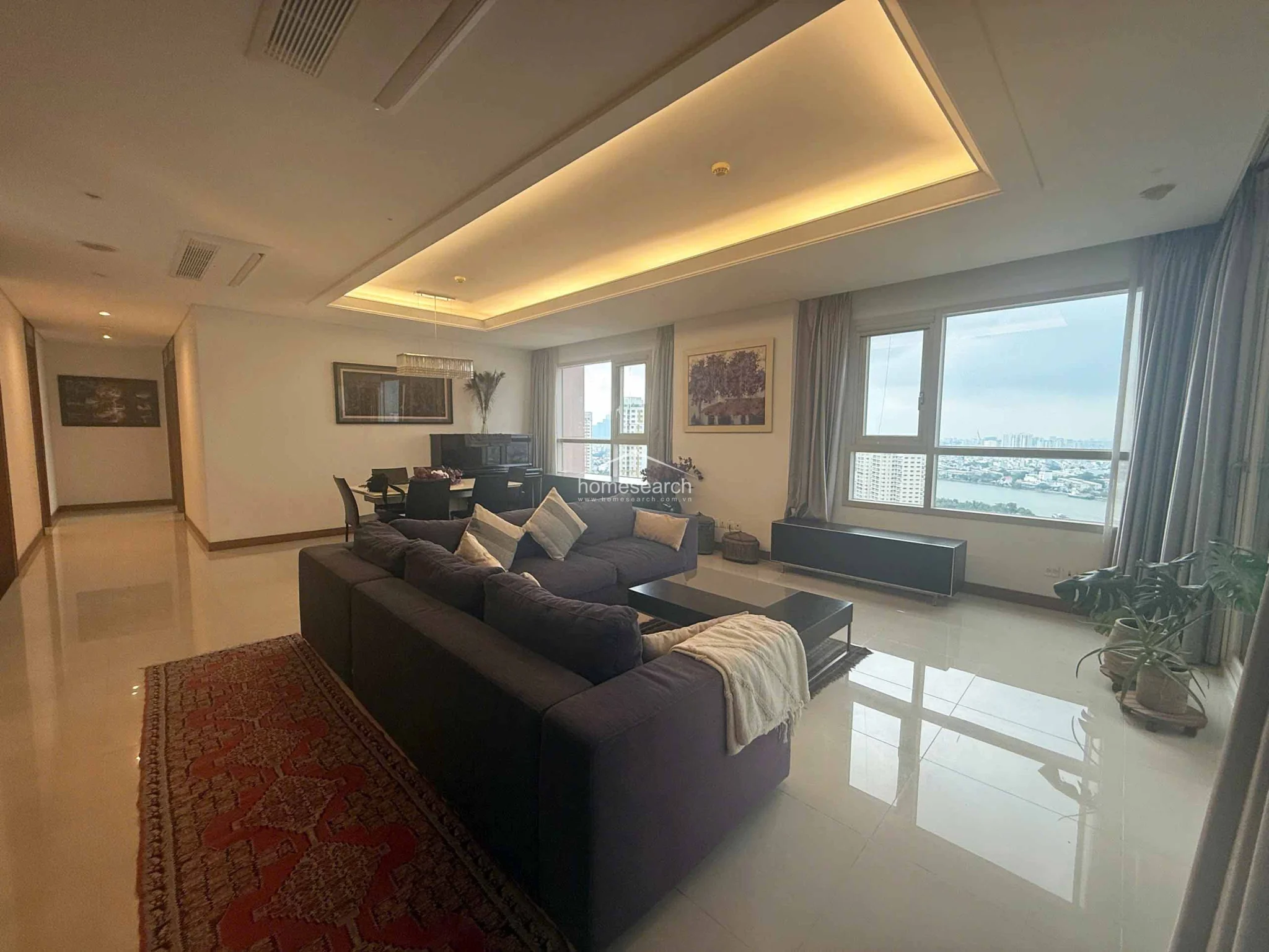 From this angle, the living area’s connection to the hallway and the rest of the unit is visible, emphasizing the generous floor plan and airy atmosphere. The minimalist design is complemented by functional built-in media storage and a consistent color scheme that promotes a clean, modern aesthetic.