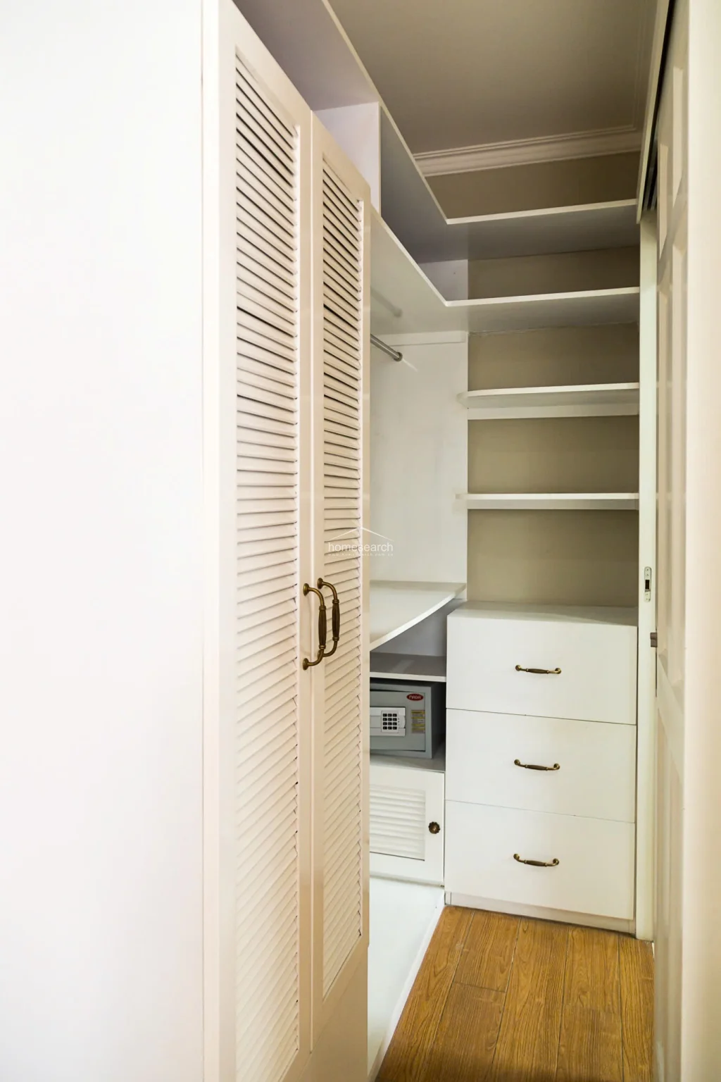 This bathroom vanity area is clean and well-maintained, featuring a white porcelain sink with a modern chrome faucet set against a backdrop of light marble-style wall tiles. The space is optimized with a wall-mounted medicine cabinet and mirror, complemented by a wooden storage stool, reflecting a practical and tidy design.