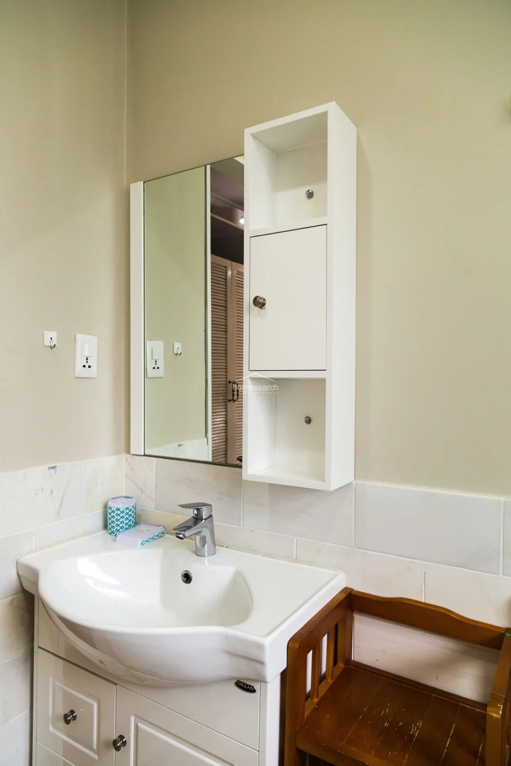 This bathroom features a clean, white soaking tub paired with a modern handheld shower fixture. The walls are finished with large, neutral-toned marble tiles that provide a bright and polished aesthetic.
